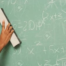 A hand erasing writing from a chalkboard.