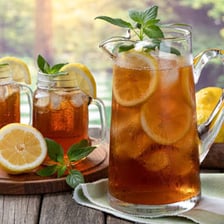 A glass of iced tea with lemon on a sunny table.