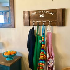 Aprons hanging in a kitchen near cooking utensils
