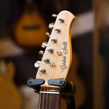 The tuning pegs on the headstock of an acoustic guitar