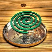 A lit spiral mosquito coil releasing insect-repelling smoke.