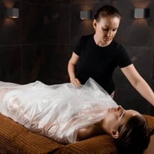 A person receiving a mud wrap treatment at a spa