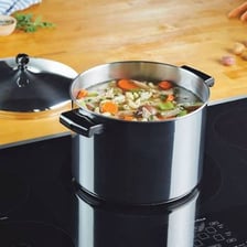 A cooking pot covered with a lid on a stove.