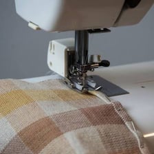 A person stitching the hem of a piece of fabric.