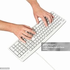 Hands entering text on a computer keyboard.