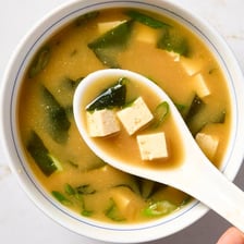 A bowl of Japanese miso soup beside a bowl of miso paste