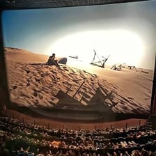 A cinema auditorium with a large IMAX screen.