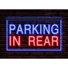 A storefront sign directing customers to parking behind the building