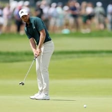 A golfer using a putter on a golf green.