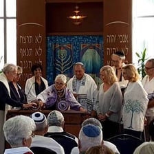 A group participating in a Jewish prayer service inside a synagogue