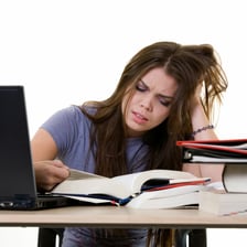 A student studying urgently with books before an exam