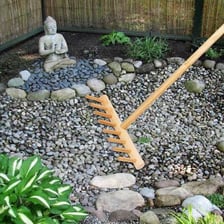 A wooden rake making patterns in a Zen garden’s gravel