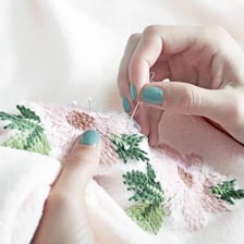 Hands stitching fabric with a needle and thread