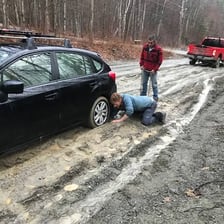 A vehicle stuck in a deep rut in a muddy road.