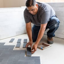 A worker installing new tiles on a bathroom floor.