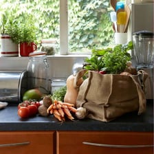 A person taking groceries out of shopping bags in a kitchen