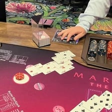 A blackjack table with a player receiving an additional card.