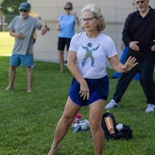 A person performs a slow tai chi movement outdoors.