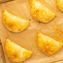 A golden folded empanada pastry on a plate.