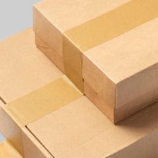 A roll of clear packing tape being used to seal a cardboard box.