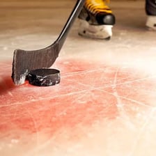 A black hockey puck resting on an ice rink
