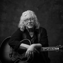 A photograph of folk singer Arlo Guthrie performing with a guitar