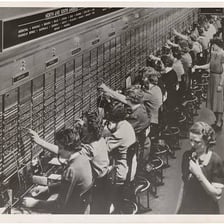 A telephone operator working at a vintage manual switchboard.