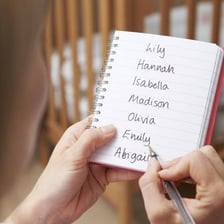 Expectant parents considering baby names in a notebook
