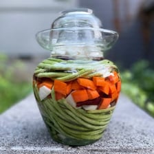 A jar of vegetables submerged in pickling liquid.