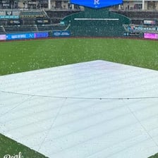 A baseball field covered by a tarp during a rain delay