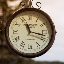 A train arriving beside a station clock at its scheduled time