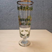 A golden pilsner beer in a glass beside hops.