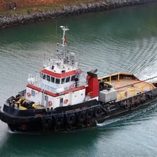 Tugboats maneuvering larger vessels in a harbor