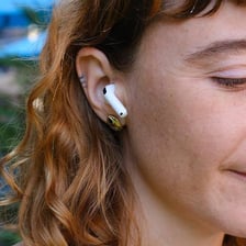 An Apple AirPod being worn in a person's ear.