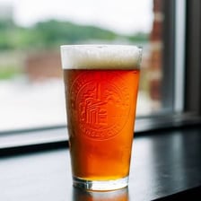 A glass of lager beer beside brewing equipment