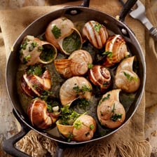 A dish of escargots is served with garlic butter.