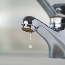 Water dripping from a household faucet.
