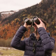 A person looking toward a distant object through binoculars.