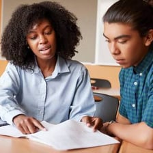 A tutor teaching a student at a desk