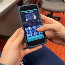 A person solving a five-letter word puzzle on a phone