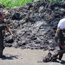 A person walking slowly and heavily along a muddy path.