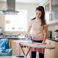 A clothes iron pressing a shirt on an ironing board