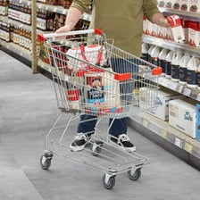 A wheeled grocery cart in a supermarket aisle.