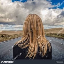 A woman standing at a distance in an outdoor landscape.