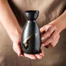 A Japanese sake bottle with a small serving cup.
