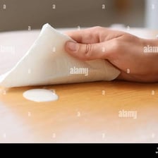 A hand gently blotting a spill with a cloth.