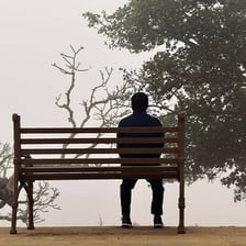 A person sitting alone in a quiet outdoor setting.