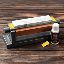 A craftsperson honing a blade with a sharpening stone.