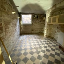 A below-ground stone cellar with visibly damp walls