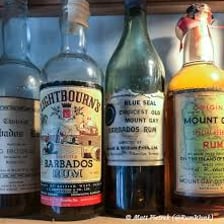 A glass of rum beside a rum bottle.